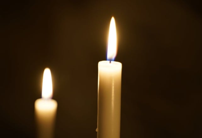 Two candles with steady flames in a dim setting, creating a quiet and reflective memorial atmosphere in Mooreland, IN.