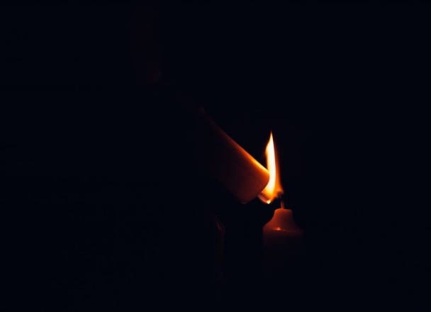 Lit candle in darkness representing funeral homes in New Castle, IN.